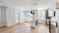 Located at 2600 Roby Corlew Ln in Murfreesboro, TN, this well-appointed 3-bedroom, 2-bathroom single-story home offers a clean, modern aesthetic throughout. Light wood-style flooring runs consistently across the space, complemented by crisp white walls and bold black hardware accents that give the interior a contemporary feel.

The open-concept living, dining, and kitchen area serves as the heart of the home, bathed in natural light from multiple windows with blinds. The kitchen is thoughtfully designed with two-tone cabinetry in white and gray, white quartz countertops, stainless steel appliances, and a central island with a built-in sink and striking pendant lighting. A door from this area leads directly to a private balcony, extending the living space outdoors.

A hallway connects the main living area to the three bedrooms, each featuring wood-style flooring, ceiling fans with lighting, closets with paneled doors, and windows that invite natural light. The bedrooms are well-proportioned, with the primary offering a generous layout and ample closet space.

Both bathrooms maintain the home's modern style with gray vanity cabinetry, white countertops, black-framed mirrors, and tub-shower combinations. A dedicated laundry room houses a full-size Whirlpool washer and dryer. Additional utility and storage spaces round out this thoughtfully laid-out home.