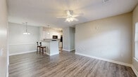 Located at 1203 Bookman Ct in Greer, South Carolina, this single-story, 2-bedroom, 2-bathroom residence offers a well-designed open-concept layout finished with consistent wood-style flooring throughout. The combined living and dining area is bright and airy, featuring ceiling fans with light fixtures, a textured ceiling, and access to an outdoor patio through a glass-panel door, allowing natural light to fill the space.

The kitchen is a standout feature, equipped with white shaker-style cabinetry, granite countertops, black appliances including a range, microwave, and refrigerator, and a peninsula with bar seating for two — ideal for casual dining or entertaining. Pendant and track lighting add a polished touch overhead.

Both bedrooms offer ceiling fans, wood-style flooring, and generous closet space. The primary bedroom includes an en-suite bathroom and access to a spacious walk-in closet with wire shelving systems. The second bedroom features a large window with outdoor views. Each bathroom is appointed with white vanity cabinetry, a tub-shower combination, and wood-style flooring.

Additional highlights include four closets for abundant storage, a dedicated laundry area, and a neutral color palette throughout that creates a clean, cohesive ambiance across the entire residence.
