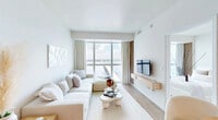 Located at 2500 Edwards Dr in Fort Myers, FL, this thoughtfully designed one-bedroom, one-bathroom residence offers an efficient yet comfortable layout with a bright, modern aesthetic. The open-concept living, dining, and kitchen area serves as the heart of the space, anchored by expansive floor-to-ceiling windows that frame sweeping waterfront views and flood the interior with natural light. Light wood-tone flooring runs throughout, complementing the crisp white walls and neutral palette.

The living area features a generous sectional sofa, a sculptural coffee table, and a wall-mounted TV, all oriented to take full advantage of the panoramic water scenery. The kitchen is outfitted with white shaker cabinetry, granite countertops, a subway tile backsplash, and a full suite of stainless steel appliances, including a refrigerator, dishwasher, and over-the-range microwave. A pantry provides additional storage.

The bedroom is a calm retreat with dual closets, floating wood shelving, and direct access to the hallway. The bathroom includes a glass-enclosed walk-in shower, granite vanity, and tile flooring. Three closets throughout the unit offer ample storage. The overall ambiance is clean, coastal, and contemporary.