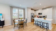Located in Jacksonville, FL (32256), this well-designed two-story home offers three bedrooms, four bathrooms, and a thoughtful layout spread across two floors. The main level features a bright, open-concept kitchen and living area with light hardwood-style flooring throughout. The kitchen is equipped with white cabinetry, stainless steel appliances, a large center island with bar seating, and recessed lighting. A dining area with a round table sits adjacent, bathed in natural light from large windows with elegant drapery. The living room is warm and inviting, anchored by a wide triple window that fills the space with natural light. A half bathroom on the main level adds convenience for guests. The attached garage is generously sized with overhead door access, built-in shelving, and a dedicated utility area. Upstairs, the primary bedroom offers a serene retreat with plush carpeting, natural light, and a walk-in closet. The en-suite bathroom impresses with marble-style tile flooring and walls, a dual-sink vanity with white cabinetry and gold hardware, and a glass-enclosed shower. Two additional carpeted bedrooms share the upper level alongside a dedicated laundry room with a full-size washer and dryer. Neutral tones and clean finishes create a cohesive, modern ambiance throughout.
