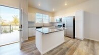 The Oasis is a well-appointed two-bedroom, two-and-a-half-bathroom residence spread across two floors, offering a comfortable and functional layout designed for modern living. The exterior features classic brick construction paired with contemporary gray siding, lending the building a polished, durable aesthetic with a private entrance.

The main level showcases light hardwood-style flooring throughout the primary living areas. The kitchen is equipped with white shaker cabinetry, granite countertops, a tile backsplash, and a full suite of stainless steel Whirlpool appliances, including a dishwasher, range, microwave, and refrigerator. A large window fills the kitchen with natural light.

A conveniently located half bath serves the main level. The in-unit laundry area houses a full-size front-loading Whirlpool washer and dryer set with additional wire shelving above for storage.

Upstairs, the bedrooms feature plush carpet flooring and generous walk-in closets outfitted with wire shelving systems for organization. One bedroom includes a ceiling fan, a wall-mounted mini-split unit, and direct access to a private en-suite bathroom. The bathrooms are finished with granite-topped white vanities and hardwood-style tile flooring.

Completing the unit is an attached garage with an epoxy-coated floor, providing secure parking and additional storage space.