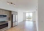 Located in Miami's vibrant Coconut Grove neighborhood, this modern single-floor residence at 2900 SW 28 Ln offers a clean, contemporary design throughout. Large-format tile flooring runs seamlessly across the living, dining, and bedroom areas, lending a cohesive and polished aesthetic to the entire space.

The open-concept living and dining area is bathed in natural light, courtesy of expansive floor-to-ceiling sliding glass doors that open to a private balcony. From here, sweeping views of the Miami skyline and lush urban greenery create a striking backdrop. The bedroom similarly benefits from oversized windows that frame panoramic city views, filling the room with abundant sunlight.

The kitchen is thoughtfully appointed with sleek, light wood-grain cabinetry, under-cabinet lighting, light-toned countertops, and a full suite of stainless steel appliances including a French door refrigerator, electric range, built-in microwave, and dishwasher. A dedicated sink station near the entry adds practical functionality.

The bathroom features a clean, modern design with wood-grain vanity cabinetry, a white countertop with an undermount sink, a large mirror, and a soaking tub with shower combination, all finished in neutral tiling. Crisp white walls throughout the residence enhance the bright, airy ambiance that defines this well-designed Miami home.