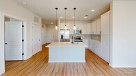 Located at 2405 Herrons Nest Pl NW in Concord, NC, this well-appointed 2-bedroom, 2-bathroom residence offers a thoughtfully designed single-floor layout. Warm wood-look flooring flows consistently throughout the home, complementing the clean, neutral color palette.

The open-concept kitchen and living area serves as the heart of the home. The kitchen is outfitted with crisp white shaker cabinetry, light quartz countertops, a subway tile backsplash, and a full suite of stainless steel appliances including a French door refrigerator, electric range, microwave, and dishwasher. A central island with an undermount sink and striking trio of pendant lights with matte black accents anchors the space and provides additional prep and seating room. The adjoining living area benefits from multiple windows that invite generous natural light.

Both bedrooms are comfortably proportioned, each featuring windows with exterior views and dedicated closets. The spacious primary bedroom offers a quiet retreat with ample room for furnishings. The two full bathrooms are finished with white vanities, light quartz counters, matte black hardware, and tub-shower combinations with white tile surrounds. Each room reflects a consistent, modern design sensibility throughout this well-lit, move-in-ready home.