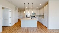 Located at 2405 Herrons Nest Pl NW in Concord, NC, this well-appointed 2-bedroom, 2-bathroom residence offers a thoughtfully designed single-floor layout. Warm wood-look flooring flows consistently throughout the home, complementing the clean, neutral color palette.

The open-concept kitchen and living area serves as the heart of the home. The kitchen is outfitted with crisp white shaker cabinetry, light quartz countertops, a subway tile backsplash, and a full suite of stainless steel appliances including a French door refrigerator, electric range, microwave, and dishwasher. A central island with an undermount sink and striking trio of pendant lights with matte black accents anchors the space and provides additional prep and seating room. The adjoining living area benefits from multiple windows that invite generous natural light.

Both bedrooms are comfortably proportioned, each featuring windows with exterior views and dedicated closets. The spacious primary bedroom offers a quiet retreat with ample room for furnishings. The two full bathrooms are finished with white vanities, light quartz counters, matte black hardware, and tub-shower combinations with white tile surrounds. Each room reflects a consistent, modern design sensibility throughout this well-lit, move-in-ready home.