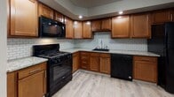 This single-floor unit offers a thoughtfully designed layout that balances functionality and comfort across its living spaces. The kitchen stands out as a highlight of the unit, featuring warm wood cabinetry, granite countertops, a classic subway tile backsplash, and a full suite of black appliances including a gas range, built-in microwave, and dishwasher. Light-toned hardwood-style flooring runs through the kitchen and main living areas, lending a clean, cohesive aesthetic throughout. The living and bedroom spaces are bright and open, with vertical blinds adorning multiple windows that invite generous natural light and offer views of surrounding greenery. Several of the rooms feature soft, neutral carpeting underfoot, while built-in closets with sliding doors provide practical storage solutions. Accent walls with subtle textured paneling add a quiet visual interest to select rooms. The bathroom is well-finished, with floor-to-ceiling large-format tile surrounding the tub-shower combination, wood-tone flooring, and a small window that brings in natural light. Baseboard heating is present throughout the unit, ensuring year-round comfort. The overall ambiance is clean, neutral, and move-in ready, offering a versatile canvas for a variety of interior styles.