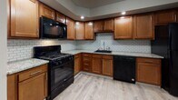 This single-floor unit offers a thoughtfully designed layout that balances functionality and comfort across its living spaces. The kitchen stands out as a highlight of the unit, featuring warm wood cabinetry, granite countertops, a classic subway tile backsplash, and a full suite of black appliances including a gas range, built-in microwave, and dishwasher. Light-toned hardwood-style flooring runs through the kitchen and main living areas, lending a clean, cohesive aesthetic throughout. The living and bedroom spaces are bright and open, with vertical blinds adorning multiple windows that invite generous natural light and offer views of surrounding greenery. Several of the rooms feature soft, neutral carpeting underfoot, while built-in closets with sliding doors provide practical storage solutions. Accent walls with subtle textured paneling add a quiet visual interest to select rooms. The bathroom is well-finished, with floor-to-ceiling large-format tile surrounding the tub-shower combination, wood-tone flooring, and a small window that brings in natural light. Baseboard heating is present throughout the unit, ensuring year-round comfort. The overall ambiance is clean, neutral, and move-in ready, offering a versatile canvas for a variety of interior styles.