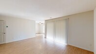 This 2-bedroom, 1-bathroom single-floor residence offers a thoughtfully organized layout that balances comfort and functionality. The open living area is a standout feature, showcasing light-toned hardwood-style flooring, neutral white walls, and a large sliding glass door dressed with vertical blinds that floods the space with abundant natural light. A ceiling fan adds to the room's practicality. The kitchen is well-equipped with dark cabinetry, granite countertops, a tile backsplash, stainless steel appliances including a refrigerator and dishwasher, and a deep sink — all complemented by the same warm flooring. A dedicated closet off the kitchen conveniently houses a stacked washer and dryer. Both bedrooms are carpeted for comfort, with the spacious primary bedroom offering a generous footprint and ample room for furnishings. The second bedroom features a charming arched window detail, bringing in natural light. The full bathroom is finished with tile flooring, a granite-topped dark vanity, and a full tub-shower combination. Two closets provide additional storage throughout the unit, rounding out this practical and move-in ready home.