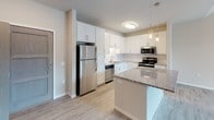 Located at 6624 Century Ave in Middleton, Wisconsin, this single-floor unit offers a thoughtfully designed layout with contemporary finishes throughout. The open-concept kitchen serves as a central highlight, featuring crisp white shaker cabinetry, granite countertops, a subway tile backsplash, and a full suite of stainless steel appliances including a gas range, microwave, dishwasher, and refrigerator. A peninsula provides additional prep space and casual seating, while pendant lighting adds a polished touch overhead.

The living area benefits from vaulted ceiling accents, a ceiling fan, and sliding glass doors that open to a private balcony with neighborhood views, allowing ample natural light to fill the space. Light wood-look flooring runs throughout the main living areas, creating a cohesive and clean aesthetic.

The bedrooms are carpeted for comfort and include ceiling fans and natural light from well-positioned windows. The primary bedroom features a closet with wood-toned sliding doors. An additional versatile carpeted room can function as a flex space or den.

The bathroom is clean and functional, equipped with a sliding glass-door shower, chrome fixtures, and a grab bar, all set against neutral walls and wood-look tile flooring.