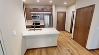 This 400 square foot apartment, located at 531 W Washington Ave in Madison, Wisconsin, offers a thoughtfully designed living space on a single floor. The open-concept layout maximizes the available area, creating a sense of spaciousness despite its compact size. The apartment features beautiful hardwood flooring throughout, adding warmth and character to the space.

The kitchen is a standout feature, boasting modern stainless steel appliances, including a full-size refrigerator, built-in microwave, and oven. Ample wood cabinetry in a light finish complements the white countertops, while a central island with a sink provides additional workspace and defines the kitchen area.

The bathroom is efficiently designed with a single vanity, toilet, and what appears to be a shower (not visible in the image). The clean, white fixtures and wood-look flooring contribute to a contemporary aesthetic.

A notable feature is the large glass door leading to an outdoor area, allowing natural light to flood the space and offering a connection to the exterior. The neutral color palette of whites and light woods creates a bright, airy atmosphere throughout the apartment.

Recessed lighting and a modern pendant light in the kitchen area provide ample illumination, enhancing the overall ambiance of this compact yet stylish urban dwelling.