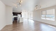 Located at 2131 Lawrence St in Denver's vibrant 80205 neighborhood, this single-floor, three-bedroom, two-bathroom home offers a well-designed layout with modern finishes throughout. The open-concept kitchen and living area serves as the heart of the home, featuring rich dark cabinetry, a white central island, pendant lighting, and a full suite of white appliances including a double oven. Large windows along multiple walls flood the space with natural light, while hardwood-style flooring adds warmth and continuity across the main living areas. The spacious living room benefits from track lighting and roller shades, creating a bright yet versatile environment. The primary bedroom is generously sized, featuring plush carpeting, a ceiling fan, and a large window with views of the surrounding neighborhood. Bedrooms are connected by a carpeted hallway that leads to closets and bathrooms. The bathrooms are finished with dark vanity cabinetry, white countertops, large mirrors, and a soaking tub with tiled surround. Walk-in closets feature wire shelving systems for organized storage. Clean white walls and consistent trim work throughout lend the home a cohesive, contemporary aesthetic.