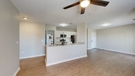 This well-appointed single-floor residence offers a thoughtfully designed open-concept layout that seamlessly connects the kitchen, dining, and living areas. The kitchen is a functional centerpiece, featuring crisp white cabinetry, light quartz countertops, a peninsula with a built-in sink, and a full suite of stainless steel appliances including a refrigerator, electric range, and over-the-range microwave. A stacked washer and dryer unit is conveniently located adjacent to the kitchen. Wood-look hard flooring runs throughout the main living areas, lending warmth and continuity to the space, while the living room benefits from multiple windows that invite generous natural light and outdoor views. A ceiling fan adds comfort to both the living area and additional rooms. The bedrooms are carpeted for added coziness, each equipped with a ceiling fan, natural light from well-placed windows, and closet storage — one featuring louvered bifold doors. The bathroom is finished with a white shaker-style vanity, light quartz countertop, matte black hardware, and a well-lit mirror. The overall design palette of neutral tones and modern finishes creates a clean, cohesive, and move-in-ready living environment.