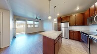 Located at 761 Wakea St in Kapolei, Hawaii, this 2-bedroom, 2-bathroom unit offers a well-designed, single-level layout ideal for comfortable island living. The open-concept kitchen is a standout feature, showcasing rich dark wood cabinetry, a tile backsplash, stainless steel appliances including a refrigerator, range, microwave, and dishwasher, and a center island with granite countertops illuminated by stylish pendant lighting. The kitchen flows seamlessly into the living area, which is equipped with a ceiling fan and windows that invite natural light and neighborhood views. Wood-style plank flooring runs throughout the unit, lending a warm, cohesive aesthetic. Both bedrooms are generously proportioned, with the primary bedroom featuring multiple windows, a ceiling fan, and a private en-suite bathroom. The second bedroom also benefits from natural light through large windows with exterior views. Each bedroom includes its own closet for ample storage. The bathrooms are finished with tiled tub-shower surrounds and neutral, clean finishes. A private balcony accessible from the living area extends the usable space outdoors, perfect for enjoying Kapolei's tropical climate.