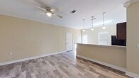 This single-floor home offers a thoughtfully designed open-concept layout that connects the living area and kitchen in a seamless, functional flow. The living room is generously proportioned, featuring warm beige walls, wood-look laminate flooring, crown molding, and a ceiling fan — details that carry consistently throughout the home to create a cohesive aesthetic.

The kitchen is well-equipped with rich, dark espresso cabinetry, granite-look countertops, and a full suite of black appliances including a refrigerator, electric range, built-in microwave, and a spacious kitchen island with pendant lighting overhead. A window above the kitchen area allows natural light to brighten the space.

The bedrooms are comfortably sized, each with the same durable wood-look flooring, crown molding, ceiling fans, and bright windows fitted with horizontal blinds that provide both privacy and natural light. The rooms offer a calm, neutral atmosphere suited for a variety of uses.

The bathroom features a full tub-shower combo with a clean white surround, coordinating hardware, and the same wood-look tile flooring that ties the space together with the rest of the home. Overall, this residence presents a clean, move-in-ready interior with consistent finishes and practical design throughout.