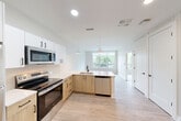 Located at 2111 Packard St in Ann Arbor, Michigan, this thoughtfully designed one-bedroom, one-bathroom unit offers a modern and efficient living experience across a single floor. The open-concept layout seamlessly connects the kitchen, dining, and living areas, creating a bright and cohesive space ideal for everyday living.

The contemporary kitchen is a standout feature, showcasing two-tone cabinetry with warm wood lower cabinets and crisp white upper cabinets, complemented by light quartz countertops and a white tile backsplash. Stainless steel appliances — including a refrigerator, electric range, over-the-range microwave, and dishwasher — provide full functionality. Pendant lighting over the peninsula adds a stylish finishing touch. Light wood-look flooring runs throughout the main living areas, enhancing the clean, modern aesthetic.

The bedroom is carpeted for comfort and features a large window overlooking a lush green outdoor setting, filling the room with natural light. A walk-in closet with wire shelving provides ample storage. The bathroom is finished with wood-look flooring, a sleek glass-enclosed shower, and clean white walls. Additional conveniences include in-unit laundry, two closets, and a utility room, rounding out this well-appointed Ann Arbor residence.