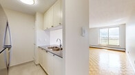 Located at 1170 Fisher Ave in Ottawa's west end, this one-bedroom, one-bathroom unit offers a well-organized and functional layout across a single floor. The living room is a bright, open space anchored by classic parquet wood flooring that extends throughout the unit, reflecting natural light from a large sliding window that opens to a balcony with sweeping city views. The galley-style kitchen is efficiently designed with cream cabinetry, ample upper and lower storage, a stainless steel double sink, dark countertops, a white subway tile backsplash, and an electric range with overhead ventilation. The kitchen connects seamlessly to the living area via a half-wall pass-through, enhancing the open feel of the space. The bedroom is a comfortably sized, quiet retreat featuring the same warm parquet flooring, a wide sliding closet, and a window that brings in natural light and additional city views. The bathroom is finished with clean white subway tile surrounding a full soaker tub and shower combination, complemented by chrome fixtures. Neutral wall tones and consistent flooring throughout give the unit a cohesive, move-in-ready aesthetic.