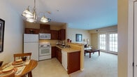 Located at 1320 Southwestern Blvd in Buffalo, NY, this single-floor residence offers a thoughtfully designed open-concept layout that seamlessly connects the kitchen, dining, and living areas. The kitchen is equipped with rich dark wood cabinetry, white appliances including a refrigerator, electric range, microwave, and dishwasher, complemented by light countertops and tile flooring. A peninsula counter with pendant lighting serves as a natural divider, opening directly to the living area. The living room features plush carpeting, warm neutral walls, and a glass-panel door that invites natural light while providing outdoor access. The bedroom is a comfortable retreat, showcasing carpet flooring, soft neutral tones, and ample natural light from a window with blinds. It offers access to multiple closets, providing generous storage. The bathroom is well-appointed with a wood-tone vanity cabinet, a large mirror with overhead lighting, a walk-in shower with sliding glass doors, and tile flooring. Throughout the residence, the consistent warm beige color palette and rich wood accents create a cohesive, welcoming ambiance suited to comfortable everyday living.