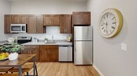 Located at 345 Chestnut St in Manchester, NH, this one-bedroom, one-bathroom unit offers a well-designed layout making smart use of its compact footprint. Light wood flooring runs throughout, creating a cohesive and warm aesthetic across all rooms.

The living area features soft gray walls, a round accent mirror, and ample room for seating and a coffee table, lending the space a clean, modern feel. It flows naturally into the spacious primary bedroom, which includes a window with outdoor views and enough room to accommodate a full sleeping and sitting area.

The kitchen is a functional highlight, outfitted with rich dark-stained shaker cabinetry, light gray quartz-style countertops, and a full suite of stainless steel appliances — including a range, over-the-range microwave, dishwasher, and refrigerator. Abundant upper and lower cabinet storage adds to its practicality.

The bathroom continues the consistent design language with a dark wood vanity, white countertop, and the same light wood flooring found throughout the unit. Three closets provide generous storage options rarely found in similarly sized spaces.

Overall, the unit presents a modern, neutral palette that is move-in ready and well-suited for those seeking a functional, stylish home in downtown Manchester.