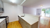 Located at 345 Main St in White Plains, NY, this thoughtfully designed single-floor residence combines modern finishes with a clean, functional layout. Warm-toned hardwood flooring runs throughout the living areas and bedrooms, creating a cohesive and inviting atmosphere.

The open living area is bright and generously sized, with soft blue-gray walls and a sliding glass door that leads to an outdoor space, allowing natural light to fill the room. A pass-through countertop connects the living area to the kitchen, enhancing the open feel.

The kitchen is well-equipped with modern wood-tone cabinetry, crisp white quartz countertops, stainless steel appliances including a gas range, microwave, and dishwasher, and ample upper and lower cabinet storage. A separate wet bar or utility area features additional cabinetry and a stainless steel sink, offering extra functionality.

The bedroom is comfortably sized with a large sliding-door closet offering built-in shelving for organized storage. A window overlooks greenery, bringing in natural light and outdoor views.

The bathroom is finished to a high standard, featuring large-format marble-look porcelain tile, a glass-enclosed shower/tub combination, a floating dark wood vanity with a white basin, and polished chrome fixtures throughout, lending a sleek, contemporary feel.