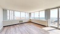 This thoughtfully designed 2-bedroom, 2-bathroom residence offers a comfortable and functional layout across a single floor. The open-concept living room is a standout feature, wrapped in floor-to-ceiling windows that frame impressive panoramic views of the city skyline and a distant body of water, flooding the space with natural light. Light-toned hardwood-style flooring runs throughout the main living areas, lending a clean, cohesive aesthetic.

The kitchen is efficiently designed with white shaker cabinetry, granite-look countertops, and a full suite of stainless steel appliances, including a range, dishwasher, microwave, and refrigerator. A breakfast bar pass-through connects the kitchen to the living area, enhancing the open flow of the space.

The spacious primary bedroom features plush carpeting, mirrored sliding closet doors, and ample room to accommodate a variety of furniture arrangements. The second bedroom is equally comfortable, also finished with light wood-style flooring and a mirrored closet. Three closets throughout the residence provide generous storage.

Both bathrooms are well-appointed: one features warm wood cabinetry with granite countertops and a tiled shower, while the second offers a clean, modern finish with a tub-shower combination and hardwood-style flooring. The overall ambiance is bright, neutral, and move-in ready.