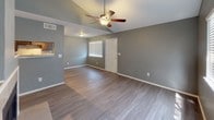 This two-floor residence offers a functional and well-appointed layout across two levels. The main living area is highlighted by vaulted ceilings and a ceiling fan, creating an open, airy atmosphere. Wood-style plank flooring runs throughout, providing a cohesive look that ties each room together. A staircase connects the two floors, with natural light filtering in through large windows dressed with horizontal blinds.

The galley-style kitchen is efficiently designed with dark espresso cabinetry lining both sides, light-toned countertops, a tile backsplash, and black appliances including a range and refrigerator. A stainless steel sink and track lighting complete the space.

The bedrooms are generously sized, each featuring ceiling fans, wood-style flooring, ample natural light from windows, and neutral gray-toned walls. Closet space is provided via sliding-door closets. The rooms offer a clean, versatile canvas suitable for a variety of furnishing arrangements.

Two full bathrooms serve the residence, each equipped with a tub-shower combination, white tile surround, and matching fixtures set against gray walls and wood-style flooring. The overall color palette of soft grays and warm wood tones lends the space a modern, understated aesthetic throughout.