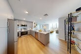 This thoughtfully designed 2-bedroom, 1-bathroom model unit at 5000 Brianna Ln in Secaucus, NJ offers a contemporary open-concept layout with stylish finishes throughout. Light hardwood flooring flows seamlessly across the entire living space, enhancing the bright, airy ambiance.

The kitchen is a standout feature, boasting sleek gray cabinetry, stainless steel appliances, a white quartz peninsula with bar seating, and a tile backsplash — ideal for both everyday living and entertaining. It opens directly into the combined dining and living area, which is bathed in natural light from expansive floor-to-ceiling windows offering outdoor views.

The generously sized primary bedroom continues the floor-to-ceiling window theme, flooding the room with light and providing scenic views. A large walk-in closet with wire shelving provides ample storage. The second bedroom is well-proportioned with convenient closet access.

The bathroom features a clean, modern design with light wood cabinetry, a white quartz vanity countertop, a large mirror, and wood-look tile flooring. Additional conveniences include an in-unit laundry area and a hallway with additional closet storage, completing this well-appointed and functional home.