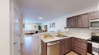 Located at 10 Townsend Lane in Brunswick, Maine, this 2-bedroom, 2-bathroom single-floor residence offers a functional and well-appointed layout. The open-plan kitchen and living area serves as the heart of the home, featuring light hardwood-style flooring throughout. The kitchen is equipped with rich walnut-toned cabinetry, white countertops, a classic subway tile backsplash, and a full suite of stainless steel appliances including a refrigerator, electric range, built-in microwave, and dishwasher. The living area provides ample room and is bathed in natural light from multiple windows, complemented by a wall-mounted mini-split HVAC unit and baseboard heating. Both bedrooms are carpeted and painted in soft blue-gray tones, each featuring a window with exterior views and baseboard heating. The primary bedroom includes access to a closet. The two bathrooms are finished with light hardwood-style flooring, wood-toned vanity cabinetry, and white countertops; one bathroom includes a tub/shower combination. The overall design is clean and contemporary, with a neutral palette that creates a bright, cohesive living environment throughout.