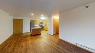 Located at 4482 47th St S in Fargo, North Dakota, this single-floor unit offers a well-designed, open-concept layout that maximizes both function and comfort. The spacious kitchen is a standout feature, equipped with warm honey-toned wood cabinetry, granite-style countertops, stainless steel appliances including a refrigerator, microwave, and dishwasher, and a central island that provides additional prep and storage space. Durable light wood-tone flooring runs throughout the kitchen area, transitioning seamlessly into the expansive living room, which is finished with rich dark hardwood-style flooring. The living room is bright and open, with a sliding glass door that leads to a private balcony and allows generous natural light to fill the space. The bedrooms are carpeted for comfort, each featuring windows for natural light, baseboard heating, ceiling fans, and spacious closets with built-in shelving and hanging rods. Two bathrooms serve the unit — one featuring a standalone shower with wire shelving for storage, and the other a full vanity with granite-style countertops. Throughout the unit, textured ceilings, wood trim, and consistent finishes contribute to a cohesive and practical living environment.