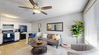 Located at 2350 E Water St in Tucson, Arizona, this single-floor unit offers a well-organized layout designed for comfortable everyday living. The open-concept living area is finished with light wood-style flooring and features a ceiling fan overhead, large windows that invite natural light, and a textured ceiling. A textured accent wall adds visual depth to the space, while a framed wall mirror enhances the sense of openness. The living area flows seamlessly into a dining counter with bar seating, creating a practical and connected gathering space. The kitchen is outfitted with white shaker-style cabinetry, light countertops, and black appliances including a refrigerator, electric range with overhead ventilation, dishwasher, and a sink — all set above matching light wood-style flooring. The bedrooms are carpeted for comfort and each includes a ceiling fan and windows fitted with horizontal blinds for light control and privacy. The neutral gray wall tones throughout the unit create a clean, cohesive aesthetic. The overall ambiance is bright, functional, and well-maintained, making this Tucson residence a practical and inviting space suited for a variety of lifestyles.