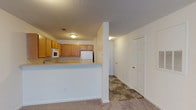 This single-floor residence offers three bedrooms and two full bathrooms within a well-organized, open layout. The living area is spacious and carpeted, flowing directly toward the kitchen, which is separated by a raised breakfast bar that doubles as additional counter space. The kitchen is fully equipped with oak-toned cabinetry, a double sink, electric range, built-in microwave, dishwasher, and a full-size refrigerator, all set atop durable tile flooring.

A hallway connects the main living space to the three bedrooms, each of which features neutral carpet, white walls, and individual windows fitted with blinds that allow for natural light. The rooms offer generous floor space suitable for a variety of furniture arrangements.

Both bathrooms are functional and consistent in design, featuring oak vanity cabinetry, a large mirror with overhead lighting, and a full tub-shower combination with chrome fixtures. A dedicated laundry room houses a full-size washer and dryer with overhead wire shelving for added storage. The textured ceilings and neutral color palette throughout create a clean, cohesive aesthetic.
