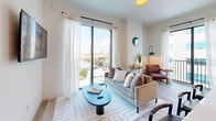 Located in Miami's vibrant Wynwood Arts District, this well-appointed 2-bedroom, 2-bathroom residence offers a thoughtfully designed open-concept layout on a single floor. Light wood flooring flows throughout, complementing a bright, neutral palette that enhances the sense of space.

The combined living, dining, and kitchen area serves as the heart of the home. The living room features floor-to-ceiling sliding glass doors that frame sweeping city views and flood the space with natural light. The contemporary kitchen is outfitted with light wood cabinetry extending to the ceiling, stainless steel appliances including a side-by-side refrigerator, a clean white tile backsplash, and a seamless countertop that doubles as a breakfast bar.

Both bedrooms offer generous closet space and large windows with outdoor views of the surrounding Miami cityscape and tropical greenery. The primary bathroom features backlit mirrors, light wood vanity cabinetry, and tile flooring. The second bathroom includes a full soaking tub and shower combination with white tile surround.

Additional conveniences include a dedicated laundry area and utility room. The overall ambiance is clean, modern, and airy — well-suited for urban living in one of Miami's most dynamic neighborhoods.