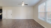 Located at 8816 Aspinwall Dr in Charlotte, NC, this one-bedroom, one-bathroom residence offers a thoughtfully designed single-floor layout. The open-concept living and kitchen area serves as the heart of the home, featuring rich dark wood-style flooring that flows throughout. The kitchen is well-appointed with dark espresso cabinetry, granite countertops, a center island with pendant lighting, and black appliances including a refrigerator with ice maker, range, over-the-range microwave, and dishwasher. Natural light filters into the living area through large windows with blinds, complemented by a ceiling fan overhead and access to an exterior door. The bedroom offers a comfortable, carpeted retreat with a large window framing outdoor greenery, multiple door access points, and a generous walk-in closet outfitted with wire shelving on multiple levels for ample storage. The full bathroom continues the granite and dark cabinetry theme, featuring a single vanity with an undermount sink, a tub-shower combination, and hardwood-style flooring. Neutral warm-toned walls throughout contribute to a cohesive and inviting ambiance across the entire residence.