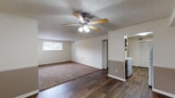 This single-floor unit located along Outer Loop in Louisville, Kentucky, offers a straightforward, functional layout spread across several distinct living areas. The main living space features a combination of dark wood-style plank flooring and a large area rug, complemented by a ceiling fan with integrated lighting and a textured ceiling. Two-tone wall treatment with a neutral gray lower half adds a subtle design detail throughout the common areas.

The kitchen is equipped with dark espresso-toned cabinetry, a tile backsplash in warm earthy tones, a double-basin stainless steel sink, and includes a range, dishwasher, and refrigerator. The adjoining dining or transitional area flows naturally between the kitchen and living space.

The bedrooms are carpeted and finished with textured ceilings, natural window light, and clean white walls, providing comfortable, quiet retreats. Each room offers adequate space for standard furnishings.

The bathroom features a full tub and shower combination with white tile surround, a vanity with a framed mirror, wall sconce lighting, and tile flooring, maintaining a clean, classic appearance throughout. Overall, the unit presents a practical and neatly organized living environment.