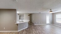 This recently renovated apartment showcases a spacious open-concept design, seamlessly connecting the living area with the kitchen. The modern kitchen boasts white cabinetry, stainless steel appliances, and a stylish herringbone backsplash. Throughout the unit, wood-look flooring and a neutral color palette create a contemporary ambiance. The living area features a fireplace and access to outdoor space. The bathroom has been updated with a white tiled shower/tub combination. Ceiling fans in multiple rooms provide comfort and air circulation. The property's layout includes additional bedrooms, offering versatility for various living arrangements.