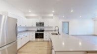 Located at 102 E Farwell Rd in Spokane, Washington, this thoughtfully designed single-floor unit offers a clean, modern aesthetic throughout its well-appointed layout. The open-concept kitchen is a standout feature, showcasing crisp white shaker-style cabinetry with matte black hardware, light grey quartz countertops, a large center island with an undermount sink and gooseneck faucet, and a full suite of stainless steel appliances including a range, microwave, dishwasher, and refrigerator. Recessed lighting and light-toned luxury vinyl plank flooring run consistently throughout, creating a bright and cohesive feel across all rooms. The living and sleeping areas are generously sized, benefiting from large windows fitted with blinds that frame open outdoor views of the surrounding Spokane landscape. A spacious walk-in closet provides ample storage with wire shelving on multiple walls. The bathroom features a full tub-shower combination, a vanity with a round mirror, and stylish black-accented fixtures. A convenient in-unit laundry closet houses a full-size washer and dryer. Additional closet storage is also available near the kitchen. A private balcony door opens to outdoor views, enhancing the sense of openness and connection to the exterior environment.