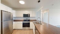 This 1-bedroom, 1-bathroom unit in Dilworth, Minnesota offers a thoughtfully designed layout that maximizes functionality and comfort. The open-concept kitchen and living area serves as the heart of the space, featuring crisp white cabinetry, warm wood-tone countertops, light luxury vinyl plank flooring, and a full suite of stainless steel appliances including a refrigerator, dishwasher, electric range, and microwave. A large central island with a clean white countertop provides additional prep space and casual seating. Pendant lighting above the island adds a modern touch. The living area extends to a sliding glass door that opens to a private balcony, allowing natural light to fill the room. The spacious bedroom offers plush carpeting, a ceiling fan with light fixture, a bright window with outdoor views, and baseboard heating. The bathroom is clean and functional, featuring a full soaking tub with shower surround. A dedicated in-unit laundry room comes equipped with a full-size Whirlpool washer and dryer, adding everyday convenience. Baseboard heating is present throughout, and the neutral color palette creates a bright, cohesive ambiance across the entire unit.