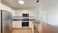 This 1-bedroom, 1-bathroom unit in Dilworth, Minnesota offers a thoughtfully designed layout that maximizes functionality and comfort. The open-concept kitchen and living area serves as the heart of the space, featuring crisp white cabinetry, warm wood-tone countertops, light luxury vinyl plank flooring, and a full suite of stainless steel appliances including a refrigerator, dishwasher, electric range, and microwave. A large central island with a clean white countertop provides additional prep space and casual seating. Pendant lighting above the island adds a modern touch. The living area extends to a sliding glass door that opens to a private balcony, allowing natural light to fill the room. The spacious bedroom offers plush carpeting, a ceiling fan with light fixture, a bright window with outdoor views, and baseboard heating. The bathroom is clean and functional, featuring a full soaking tub with shower surround. A dedicated in-unit laundry room comes equipped with a full-size Whirlpool washer and dryer, adding everyday convenience. Baseboard heating is present throughout, and the neutral color palette creates a bright, cohesive ambiance across the entire unit.
