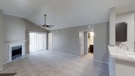 This single-story residence offers a thoughtfully designed layout with a warm, neutral color palette and practical finishes throughout. The living room serves as the heart of the home, boasting vaulted ceilings that lend an airy, open feel, a ceiling fan, and a classic white-mantled fireplace that adds a cozy focal point. Sliding glass doors allow natural light to pour in and provide access to the outdoors. The kitchen is designed for functionality, featuring dark espresso cabinetry with raised-panel doors, light granite-style countertops, a breakfast bar peninsula, and a full suite of black appliances including a range, microwave, and refrigerator. Wood-look flooring anchors the kitchen space, while plush carpet flows seamlessly through the living and sleeping areas. The bedrooms are generously sized with neutral walls, textured ceilings, and ample closet space. The bathrooms are well-appointed, each featuring dark wood vanities, light stone-patterned countertops, large mirrors with vanity lighting, and a tub-shower combination with white tile surround. Every room reflects a clean, move-in-ready aesthetic that balances comfort and practicality.
