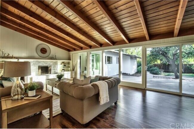 La cálida entrada se abre a una amplia sala de estar y comedor con ricas vigas de madera y luz natural. - 332 E Deodar St