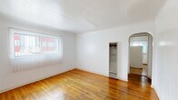 Located at 1522 Tijeras Ave NE in Albuquerque, New Mexico, this single-floor, one-bedroom, one-bathroom unit offers a practical and straightforward layout within a compact footprint. Warm-toned hardwood flooring runs throughout the living room and bedroom, lending a classic character to the space and reflecting natural light from the windows.

The living room is entered through a solid, dark-stained wood front door and features a small window that allows in additional natural light. The bedroom is a cozy, well-defined space with a window fitted with blinds and vertical shades, offering views to the exterior and bringing in ample daylight.

The kitchen is efficiently arranged along one wall, featuring white cabinetry both above and below the counter, a double-basin stainless steel sink, a gas range, and light tile flooring. A water heater is also housed within the kitchen area. The layout maximizes the use of available counter and storage space.

The bathroom is accessible via the hallway and includes a toilet, a vanity with white cabinetry, a mirror, a tall storage cabinet, and tile flooring. A closet and hallway round out the unit's layout, providing additional storage and connectivity between rooms. Throughout, the white walls and clean finishes create a bright, neutral atmosphere.