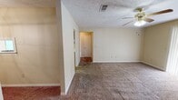 Located at 4315 Highway 39 N in Meridian, Mississippi, this single-floor, 2-bedroom, 1-bathroom home offers a straightforward and functional layout. The living room serves as the central gathering space, featuring plush carpeting, a ceiling fan with light fixture, and a sliding glass door covered by vertical blinds that allows natural light to filter in. Adjacent to the living area, the galley-style kitchen is outfitted with white cabinetry, wood-trimmed accents, white appliances including a coil-top electric range and refrigerator, and warm hardwood flooring — a practical workspace with direct access to the rest of the home. Both bedrooms are carpeted and equipped with ceiling fans. The primary bedroom offers a generous footprint with a dedicated closet, while the secondary bedroom includes a window with blinds providing natural light. Two hallways connect the rooms, supporting smooth circulation throughout the home. The full bathroom includes a tub/shower combination with a curtain rod and tile flooring. A dedicated closet provides additional storage. The textured ceilings and neutral warm-toned walls present throughout give the home a consistent, cohesive appearance well-suited for comfortable everyday living.