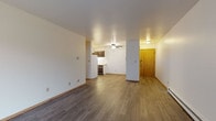 Located at 3728 S 43rd St in Milwaukee, Wisconsin, this single-floor unit offers a functional and straightforward layout designed for comfortable everyday living. The open living and dining area is finished with light wood-style laminate flooring and crisp white walls, creating a clean, bright atmosphere. A ceiling fan overhead provides air circulation, while a sliding glass door floods one end of the space with natural light and offers access to the outdoors, complemented by a wall-mounted air conditioning unit and baseboard heating along the perimeter. The galley-style kitchen is efficiently arranged with dark wood cabinetry above and below, light countertops, a double sink, and white appliances including a refrigerator and electric range. Adjacent to the main living area, the entry features a warm wood-toned door. The bedroom is carpeted for comfort and includes a window with blinds that allows natural light while maintaining privacy, along with baseboard heating. The bathroom includes a vanity with a wide countertop, dark wood cabinetry, a large mirror, and a tub/shower combination accented with classic light blue tile surround. Wood-style flooring extends throughout the bathroom, tying the space together cohesively.