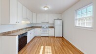 Located at 901 Charles St in Morgantown, West Virginia, this two-floor unit offers a straightforward, functional layout with consistent finishes throughout. The main living area features smooth hardwood-style flooring that reflects natural light, contributing to a bright and open atmosphere. A sliding glass door fitted with vertical blinds provides direct access to an outdoor space while drawing in additional natural light, creating a welcoming environment.

The galley-style kitchen is efficiently designed with white cabinetry accented by gold hardware, laminate countertops, and a full suite of appliances including a white refrigerator, electric range, and dishwasher. A window at the end of the kitchen allows natural light to flow through the space.

The bedrooms are carpeted and well-lit by windows with blinds. At least one bedroom features a spacious walk-in closet with a hanging rod. A primary bedroom includes an en-suite vanity area with a white cabinet, mirror, and lighted fixture, alongside access to a bathroom equipped with a soaking tub. The clean white walls and neutral tones throughout the unit create a cohesive, move-in-ready aesthetic across both floors.