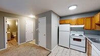 Located at 2614 E Fountain Blvd in Colorado Springs, Colorado, Unit 106 is a single-floor residence designed for comfortable, everyday living. The open layout connects the living area and kitchen, creating a practical and cohesive flow throughout the space.

The kitchen is well-equipped with warm oak-toned cabinetry offering generous upper and lower storage, light gray laminate countertops, a double-basin sink, and white appliances including a refrigerator, electric range, and dishwasher. Light wood-style flooring runs through the kitchen, providing a clean, easy-to-maintain surface.

The living area is carpeted in a neutral beige tone and features a large window with vertical blinds, allowing natural light to brighten the room. The soft, neutral gray walls and textured ceilings carry throughout the space, creating a consistent and understated aesthetic.

The bedroom is generously sized with plush carpet flooring, neutral gray walls, and a sliding-door closet with a built-in hanging rod. A hallway with additional door access connects the main living areas to the private spaces.

The bathroom features wood-style tile flooring, a white tiled tub and shower combination, a toilet, and a vanity with a white finish. The overall design of the unit is practical and move-in ready, offering a straightforward layout suited for a variety of lifestyles.