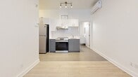 Located at 2238 Rue du Souvenir in Montréal, this efficient one-bedroom, one-bathroom unit offers a well-organized layout across a single floor. The interior presents a clean, modern aesthetic throughout, characterized by bright white walls, light wood-tone flooring in the living areas, and consistent neutral tiling in the kitchen and bathroom.

The kitchen is a functional highlight of the space, featuring two-tone cabinetry with white upper cabinets and slate grey lower cabinets, a white subway tile backsplash, stainless steel appliances including a refrigerator and electric range, and a ventilation hood. Track lighting overhead and a wall-mounted mini-split air conditioning unit add both practicality and comfort to the area.

The bedroom is a cozy, intimate space with light hardwood flooring, crisp white walls, and a window that allows natural light to filter in. A baseboard heater provides supplemental warmth during cooler months.

The bathroom features a full soaking tub with large-format white subway tile surround, neutral floor tiling, and a window that introduces natural light. The overall design across all rooms is minimal and clean, creating a cohesive, move-in-ready atmosphere well-suited for single occupancy in the heart of Montréal.