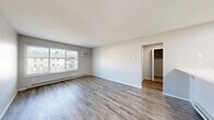 Located at 1105 S Wheeling St in Oregon, Ohio, this one-bedroom, one-bathroom unit offers a practical and well-organized single-floor layout. The combined kitchen and living area forms the heart of the unit, featuring durable hardwood-style flooring throughout and neutral gray walls that create a clean, bright atmosphere. Large sliding windows in the living area allow natural light to fill the space while providing views of the surrounding community. A wall-mounted air conditioning unit and baseboard heating system ensure year-round comfort. The kitchen is outfitted with crisp white cabinetry extending to the upper and lower sections, white laminate countertops, a double-basin stainless steel sink, and a white electric range — offering a tidy and functional cooking space. A hallway connects the main living area to the private bedroom, which features soft wall-to-wall carpeting, a dedicated window for natural light, and access to the bathroom. The full bathroom includes a white tiled tub-shower combination and standard fixtures. Notably, the unit provides an exceptional amount of storage with four closets distributed throughout. The overall design is straightforward and functional, making efficient use of the available floor area.