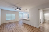 Located in Spring, TX, this single-story 1-bedroom, 1-bathroom home offers a clean, modern aesthetic with thoughtful design details throughout. The open-concept living and kitchen area serves as the heart of the home, featuring warm luxury vinyl plank flooring, crisp white walls, and abundant natural light streaming through blinded windows. A ceiling fan overhead keeps the space comfortable, while pendant lighting above the kitchen peninsula adds a stylish focal point. The kitchen is well-appointed with white shaker cabinets accented by matte black hardware, white quartz countertops, a subway tile backsplash, stainless steel appliances including a refrigerator and dishwasher, and a built-in wine rack. The spacious bedroom includes a ceiling fan, natural light from a large window, and access to a dedicated closet. The bathroom features a soaking tub with a tiled surround and matte black fixtures, complemented by the same consistent flooring found throughout the home. Stylish gray panel doors with black hardware add a modern contrast to the neutral palette. A dedicated laundry room with overhead wire shelving provides convenient in-unit functionality. The hallway connects all areas efficiently, completing this well-designed, move-in-ready home.
