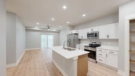 Located at 8801 Mohave Dr in Lincoln, Nebraska, this well-appointed 2-bedroom, 2-bathroom single-floor home offers a thoughtfully designed layout with modern finishes throughout. The open-concept kitchen and living area serves as the heart of the home, featuring light hardwood-style flooring, recessed lighting, and a ceiling fan. The kitchen is outfitted with crisp white shaker cabinetry, stainless steel appliances including a refrigerator, range, and over-the-range microwave, and a central island with a double sink and white countertops. A dedicated pantry provides additional storage directly off the kitchen. The living area opens to a private balcony through sliding glass doors, filling the space with natural light. The spacious primary bedroom features plush carpeting, a ceiling fan, and access to a walk-in closet with built-in wood shelving. The second bedroom is similarly carpeted and includes a ceiling fan and a window for natural light. Both bathrooms reflect the home's clean aesthetic, with white cabinetry featuring black hardware and light wood-style flooring. A tub-shower combination is present in the secondary bathroom. Throughout, neutral gray walls and consistent finishes create a cohesive, contemporary ambiance.