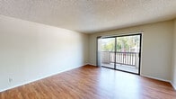 Located at 11818 Riverside Dr in the Valley Village neighborhood of Los Angeles, this one-bedroom, one-bathroom unit offers a well-organized single-floor layout. Warm wood-style flooring runs throughout, complementing the neutral wall tones and textured ceilings found across the living spaces. The open living room is bright and airy, anchored by large sliding glass doors that lead to a private balcony with greenery views — allowing natural light to fill the room throughout the day. A ceiling fan adds comfort to the living area. The galley-style kitchen is efficiently designed with warm oak cabinetry, tile countertops, and white appliances including a gas range and microwave. A breakfast bar peninsula connects the kitchen to the living space, providing additional prep and seating area. The bedroom is comfortably sized, featuring mirrored sliding closet doors, a window with outdoor views, and the same wood-style flooring. The bathroom offers a wide vanity with ample counter space, a large mirror with built-in lighting, and plentiful storage via lower cabinetry. A hallway connects the main rooms, completing the practical and cohesive layout of this Los Angeles residence.