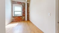 Located at 1418 W Marshall St in Richmond, Virginia, this 2-bedroom, 3-bathroom unit offers a distinctive blend of industrial charm and functional living. The space is characterized by striking exposed brick walls, which lend a warm, historic character throughout. Rich hardwood floors extend across the bedrooms and living areas, complementing the bright, white walls and creating an inviting atmosphere.

The combined kitchen and living room serves as the heart of the unit. The kitchen features a peninsula with granite-style countertops, white cabinetry, tile flooring, and full appliances including a range, microwave, refrigerator, and dishwasher. The arched brick window surrounds in the living area add architectural interest, while natural light flows freely through the windows, offering views of the surrounding Richmond cityscape.

The two bedrooms are well-proportioned, with the primary bedroom providing a comfortable and private retreat. Three closets are distributed throughout the unit, offering practical storage. The three bathrooms are clean and functional, each featuring tiled flooring, a tub-shower combination, and vanity with mirror. With three closets spread across the unit, storage is well-considered. The overall layout is efficient and cohesive, making excellent use of the available space.