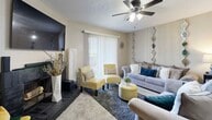 This efficiently designed one-bedroom, one-bathroom home makes excellent use of its single-floor layout, offering a comfortable and cohesive living experience. The combined living and dining area serves as the heart of the home, where the living room features plush carpeting, a ceiling fan with light fixture, a tiled wood-burning fireplace, a wall-mounted television, and sliding glass doors framed by vertical blinds that invite natural light. Decorative mirror panels accent the neutral-toned walls, adding visual depth to the space. Adjacent to the living area, the dedicated dining nook accommodates a round table with seating for four, decorated with tasteful wall art. The kitchen is efficiently arranged with warm wood-toned cabinetry, light-colored countertops, stainless steel appliances including a refrigerator and dishwasher, and durable wood-look flooring. The bedroom offers a quiet retreat with carpeted flooring, a ceiling fan, a window with blinds for natural light and privacy, and a textured ceiling consistent throughout the home. The bathroom features a wood-vanity with single-sink, a large mirror with overhead lighting, and wood-look flooring. Each room reflects a warm, functional design suited for comfortable everyday living.